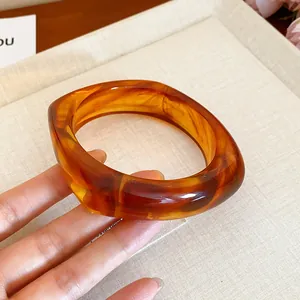 Detail view of a square amber marbled resin bangle with elegant tortoiseshell patterns