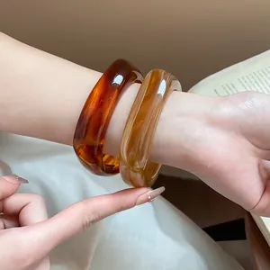 Detail view of stylish tortoise shell resin square bangles worn on a model's wrist