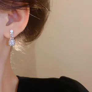 Close-up of elegant water drop zircon earrings worn on the ear, luxury style