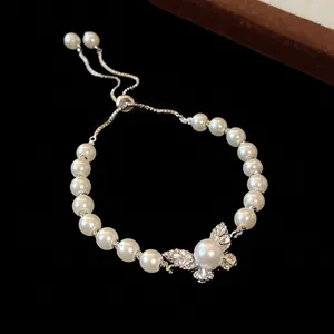 Elegant pearl bracelet with a sparkling diamond butterfly charm and adjustable sliding chain.