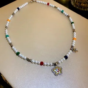 Nahaufnahme einer bunten Perlenkette mit glitzerndem Blumenanhänger und Herzanhängern.