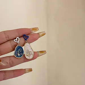Close-up of asymmetric blue and white heart earrings with romantic couple silhouettes
