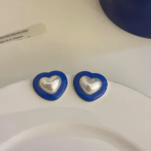 Detailed close-up of vintage heart-shaped blue enamel earrings with a pearlescent center