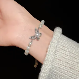 Close-up of elegant rhinestone butterfly and pearl adjustable bracelet on a wrist.