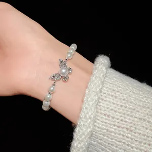 Detail of elegant faux pearl bracelet with a sparkling rhinestone butterfly charm
