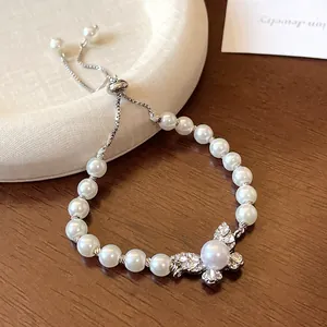 Close-up of elegant butterfly charm and white pearls on an adjustable silver bracelet