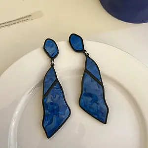 Detailed close-up showing the irregular blue marble texture on geometric earrings