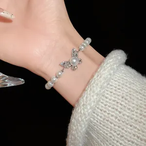 Detailed view of elegant rhinestone butterfly and faux pearl adjustable bracelet worn on wrist