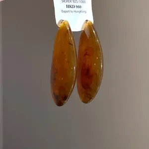 Dettaglio di orecchini a goccia d'ambra con ago in argento 925 su cartellino espositivo