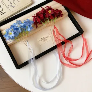 Elegante par de horquillas de flores de tela con largas cintas fluidas en estuche.