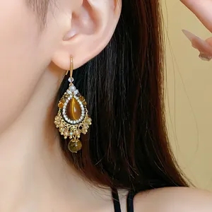 Close-up detail of ethnic vintage drop earring with tiger eye stone and crystals