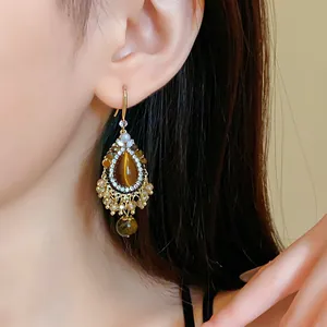 Detail view of a vintage faux tiger eye teardrop earring worn by an Asian model.