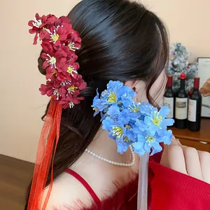 Detalle de horquillas de tela con flores rojas y azules y borlas de cinta de seda suave