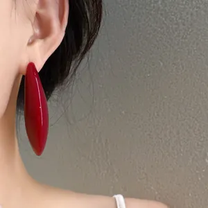 Primo piano di un orecchino a goccia rosso lucido indossato da una modella, retrò