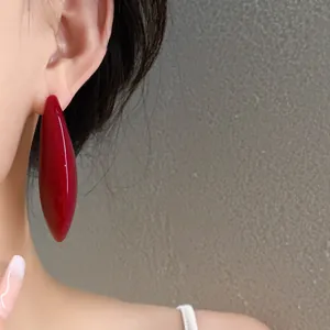 Dettaglio di un orecchino a goccia in resina rossa vintage indossato su un modello