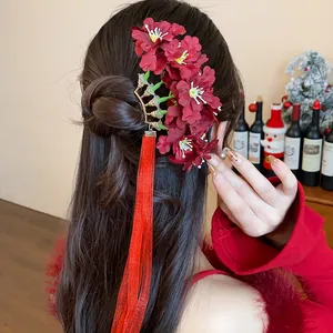 Primer plano de horquilla de flores de tela roja con borlas largas en cabello ondulado