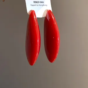Dettaglio ravvicinato di orecchini ovali a goccia rosso acceso con finitura lucida