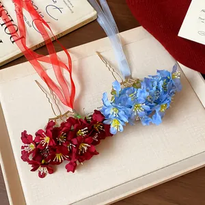 Primer plano de horquillas de flores de tela con cintas elegantes en colores rojo y azul.