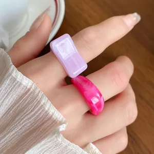 Detailed close-up showing marbled acrylic geometric rings in purple and pink on hand