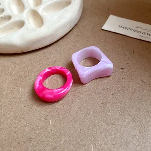 Close-up view of irregular marble pattern acrylic rings in pink and lavender purple colors.