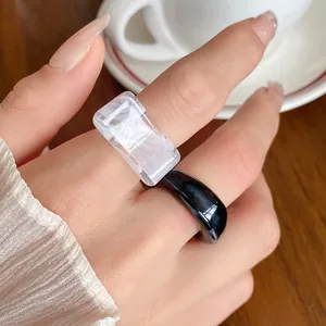 Close-up view of irregular black and white marbled acrylic geometric rings on finger