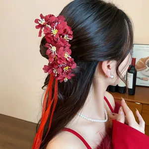 Detalle de una elegante pinza para el pelo con flores de tela roja y cintas largas en modelo