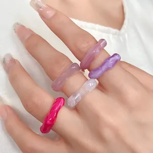 Macro view of colorful irregular acrylic rings with marble pattern on fingers.