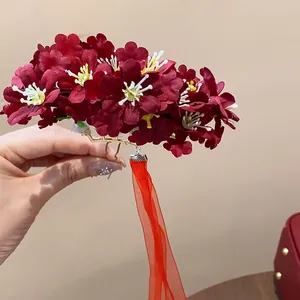 Detalle de una horquilla de flor de tela rojo vino con borla de cinta de seda.