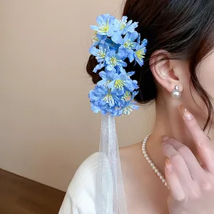 Primer plano de horquilla de flores de tela azul con elegante cinta blanca en modelo