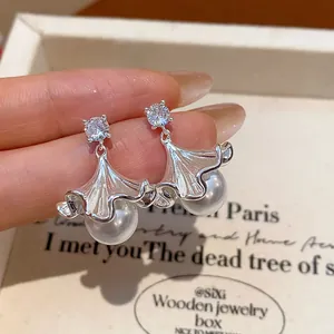 Detailed view of silver ginkgo leaf earrings with cubic zirconia and pearl dangles
