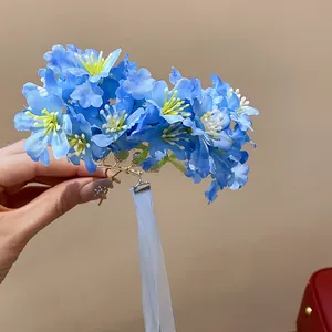 Primer plano de horquilla de flor de tela azul con borla de cinta blanca larga