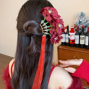 Detalle de horquilla de flor de tela roja con cintas largas en un ambiente festivo