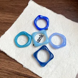 Close-up macro view of five irregular marbled acrylic geometric rings in various blue tones