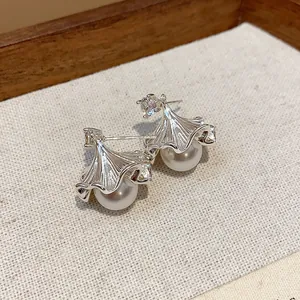 Close-up of elegant ginkgo leaf pearl stud earrings with zircon accent