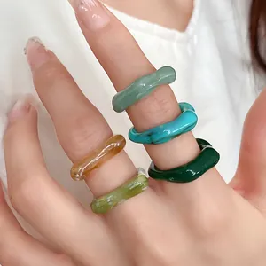 Macro detail of irregular marbled acrylic rings in multiple colors on fingers for women