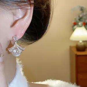 Close-up view of elegant silver ginkgo leaf earrings with white pearls and zircon