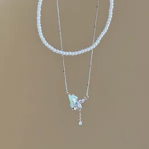 Exquisite close-up detail of a double-layered pearl and sparkly butterfly pendant necklace