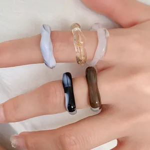 Close-up of colorful irregular marbled acrylic rings with artistic wavy geometric design