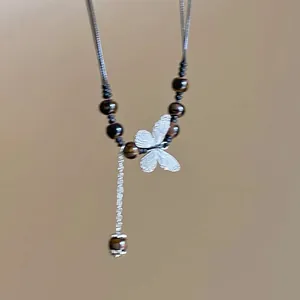 Detailed view of an elegant silver butterfly pendant necklace accented with tiger eye beads