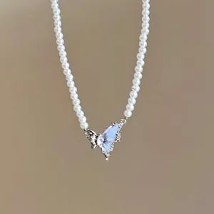 Detailed view of an elegant blue butterfly pendant integrated into a white pearl necklace