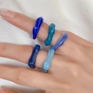 Macro detail of blue marbled acrylic rings with irregular geometric design on hand