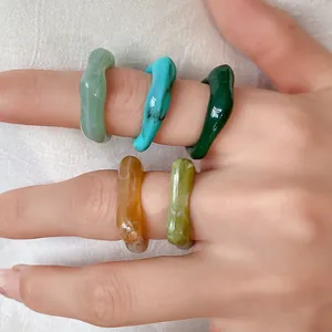 Detailed view of colorful irregular acrylic rings with marbled smudge pattern on hand