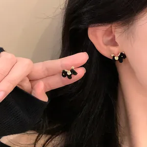 Minimalist black flocked horse stud earrings with gold accents worn on ear