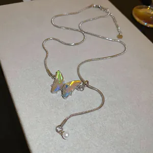 Detailed view of iridescent butterfly pendant necklace with pearl accent on silver chain