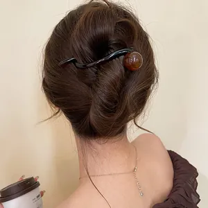 Detailed close-up showing an elegant brown resin wavy hair clip styled in a hair bun