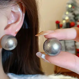 Primo piano di un elegante orecchino a bottone grigio metallizzato con perno in argento.