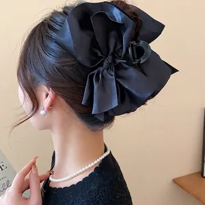 Elegant large black fabric bow hair claw clip for women shown on an Asian model