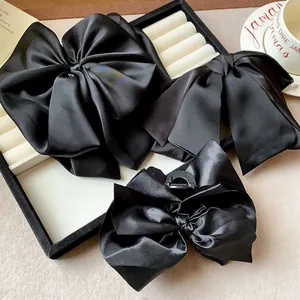 Close-up of black satin bow hair clips set showing elegant fabric texture and styles.