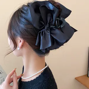 Detailed macro view of an elegant large black satin bow hair claw clip for women