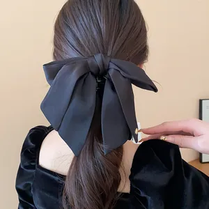 Close-up back view of a woman wearing a large black fabric bow hair claw clip.